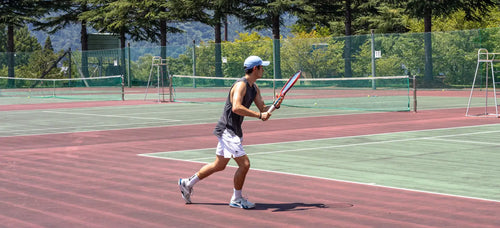 man playing tennis on hard court with tennis elbow