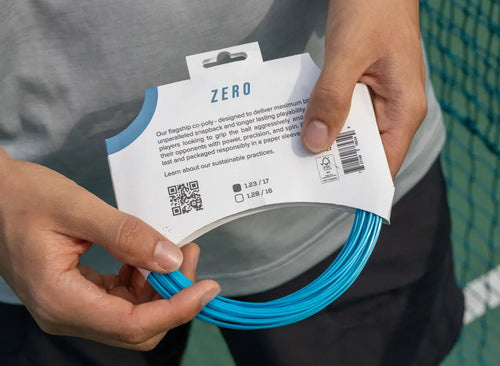 man holding restring zero tennis string in its packaging
