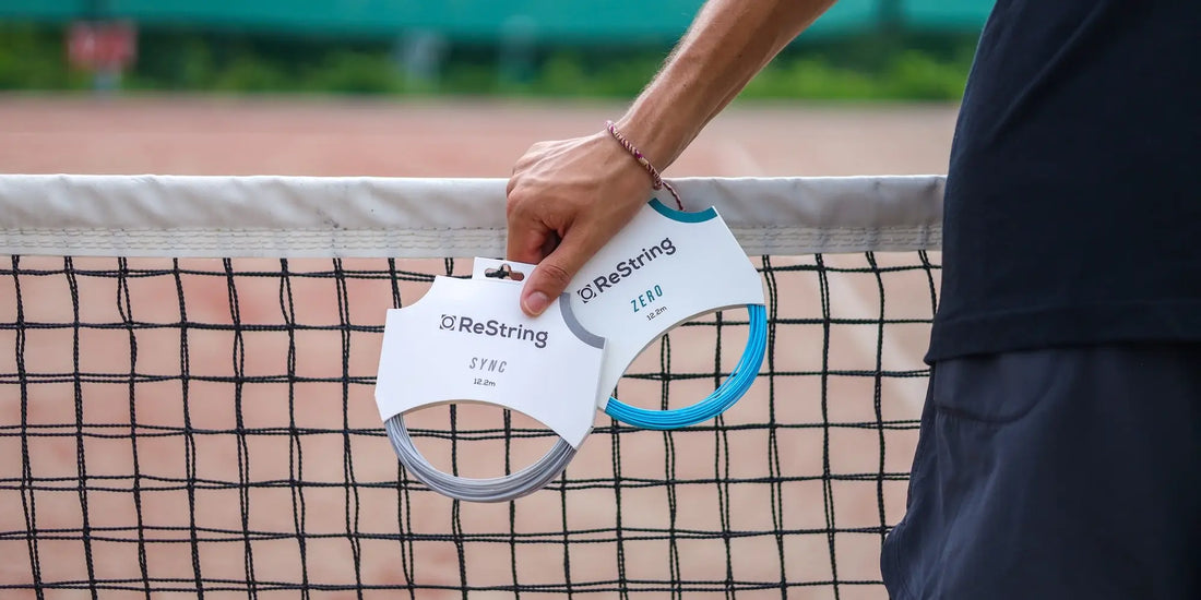 man holding shaped string and round tennis string leaning against tennis net