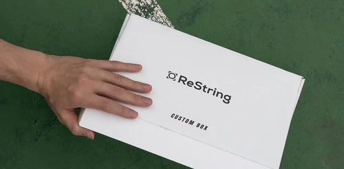 man's hand holding ReString paper tennis string box
