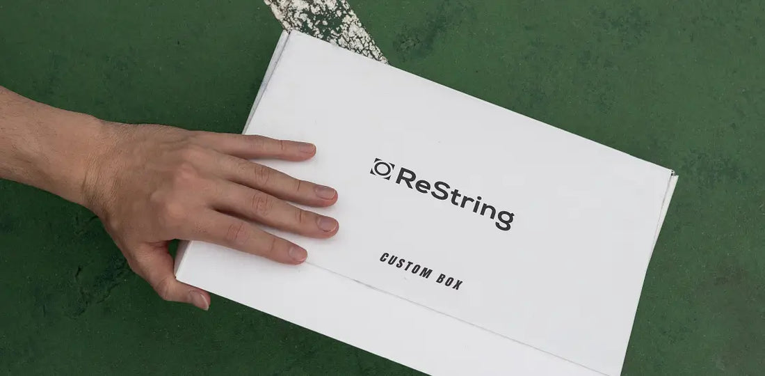 man's hand holding ReString paper tennis string box